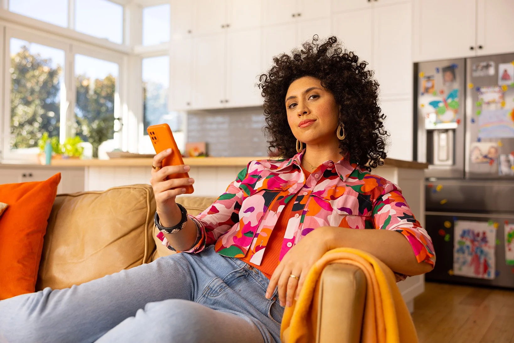 Everyday Mobile lifestyle imagery of a woman at home with an orange phone